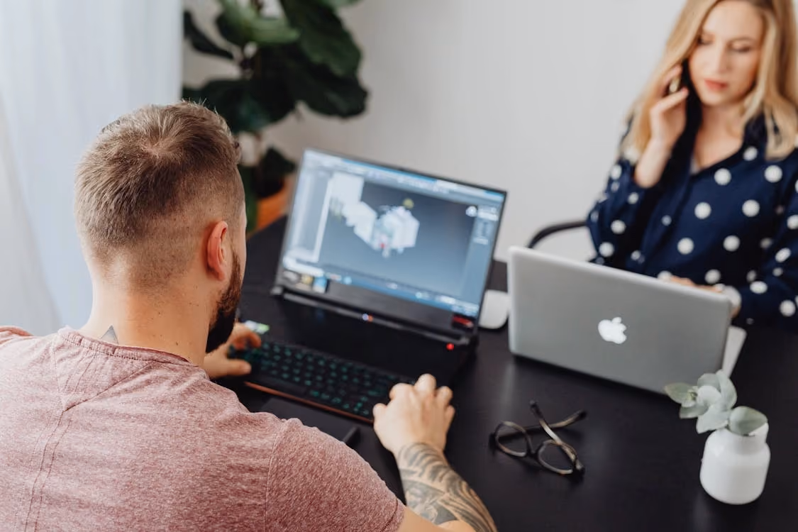 Two people working on a 3D project on their computers