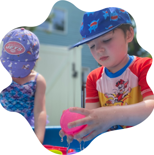 Young girl in a pink sleeveless top and shiny pink cap playing on playground equipment.