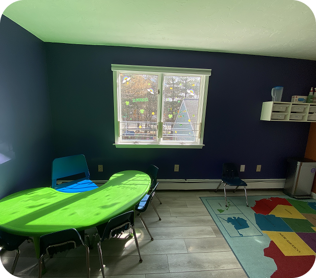 Children's playroom area with a toy kitchen set, blue baby seat, and a tall shelf filled with organized colorful toys and educational blocks next to foam climbing blocks.