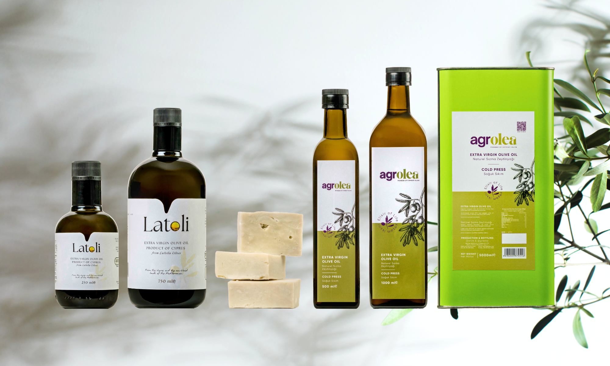 Range of olive oil products including small and large Latoli bottles, two Agrolea bottles, Agrolea tin, and olive soap with olive branches.