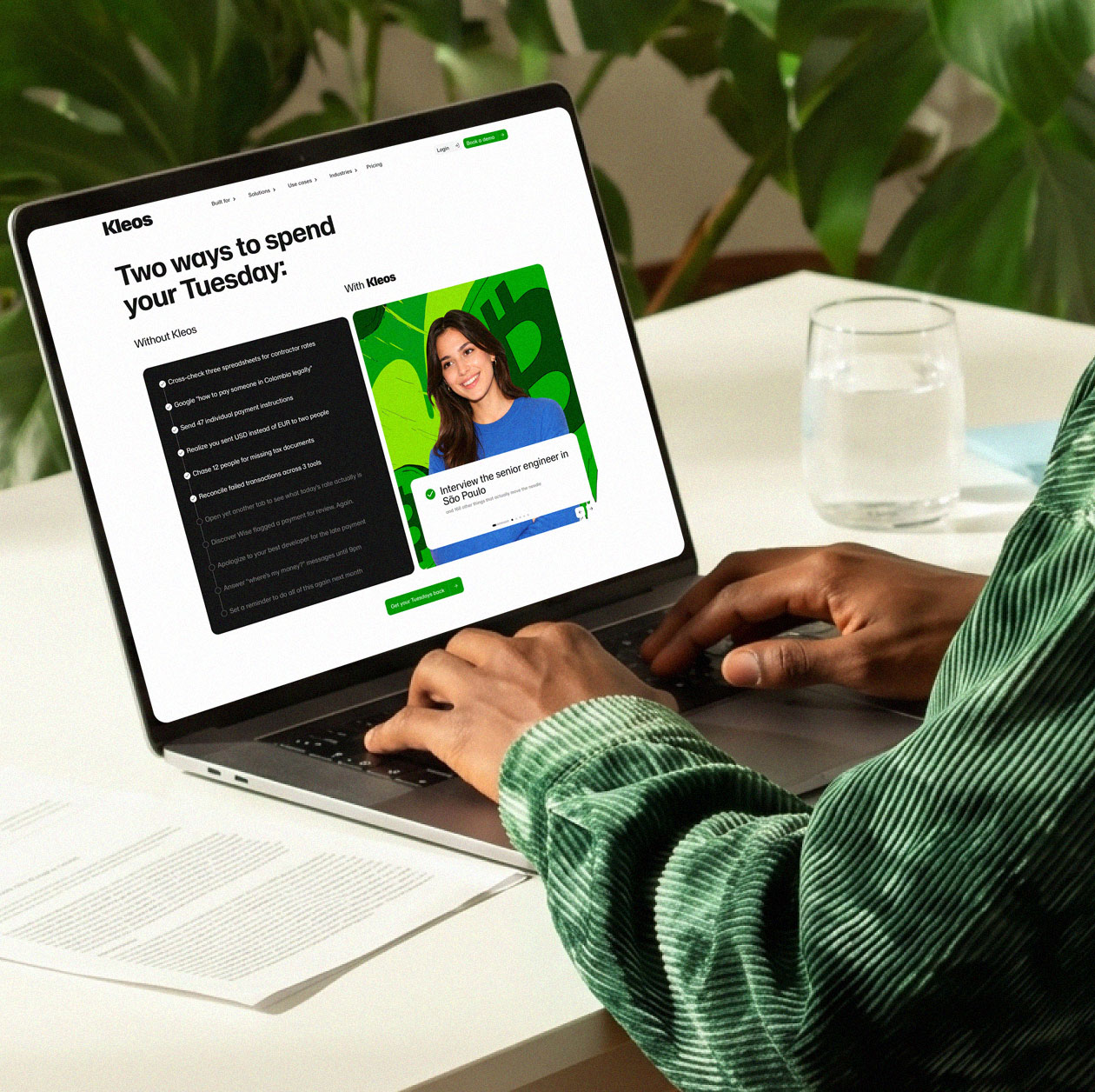 Person in a green shirt browsing the Kleos website on a laptop at a desk