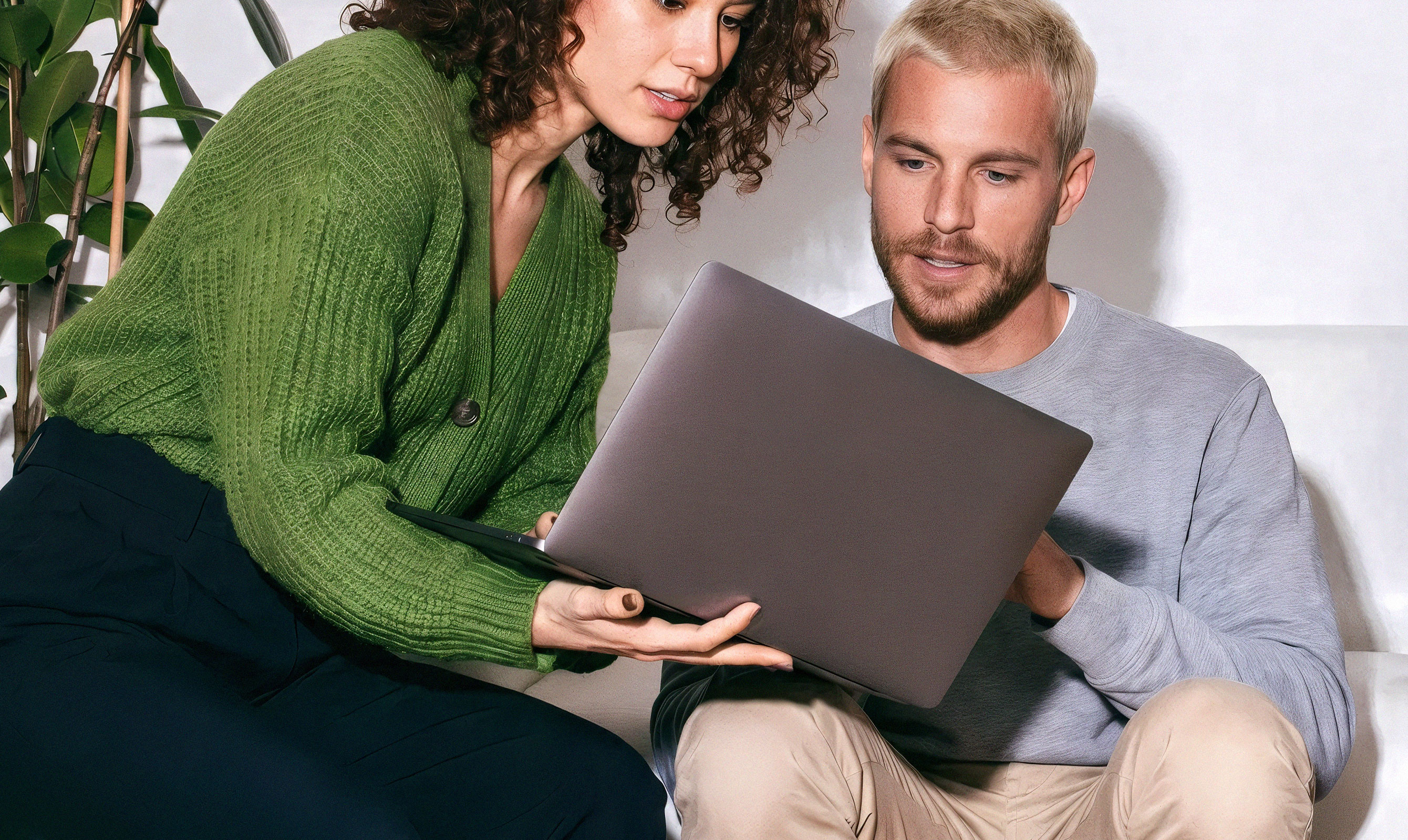 Two colleagues sitting together reviewing content on a laptop