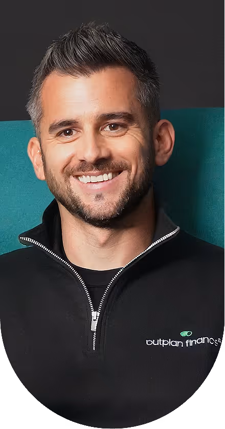 Smiling man with short gray and brown hair and a trimmed beard, wearing a black quarter-zip sweater with Outplan Finance logo.