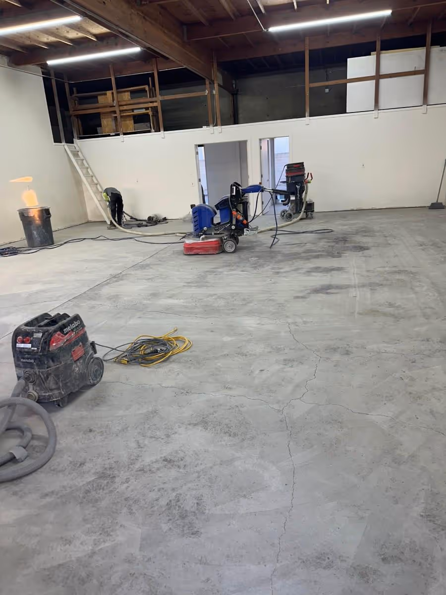 Bare warehouse slab being prepared with grinders and dust extraction before coating