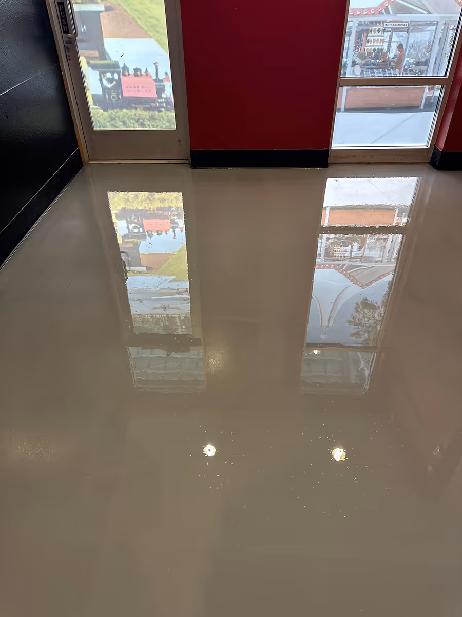 High gloss cream commercial floor reflecting the glass entrance doors and the street outside