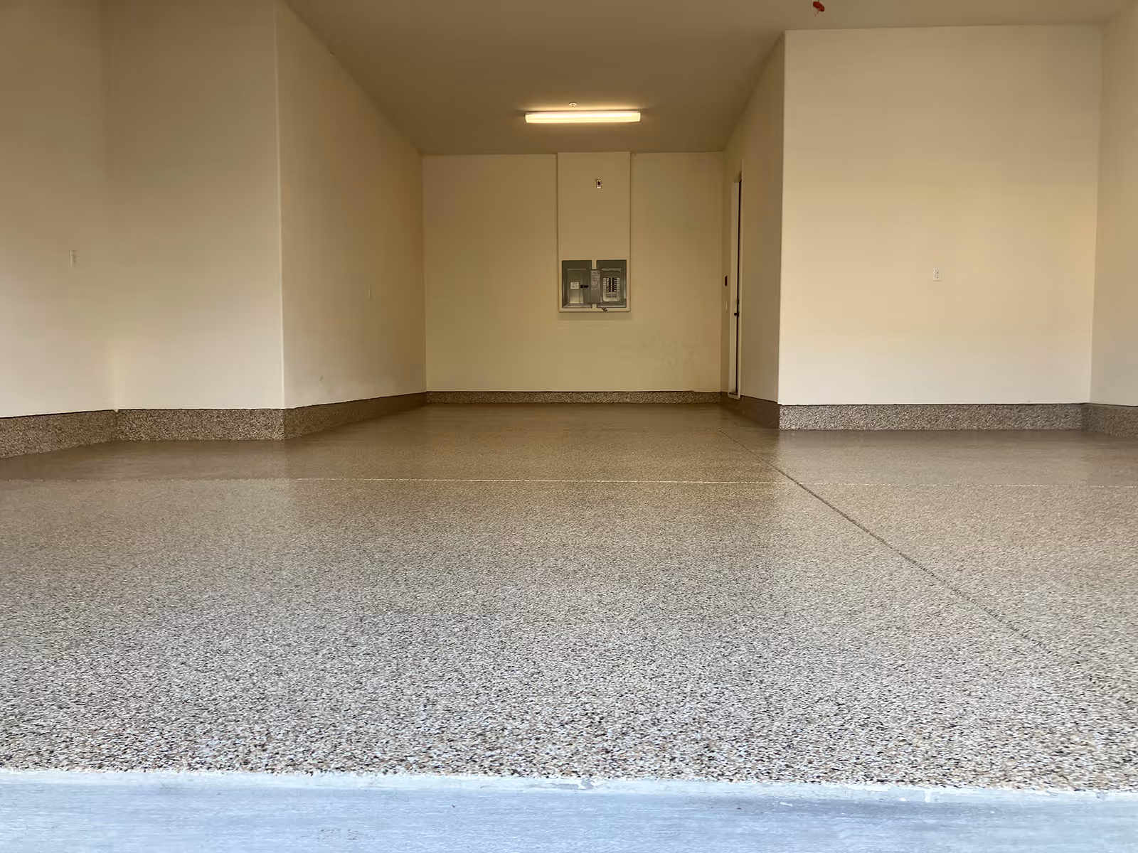 Empty garage with a flake floor and a coved base to the walls