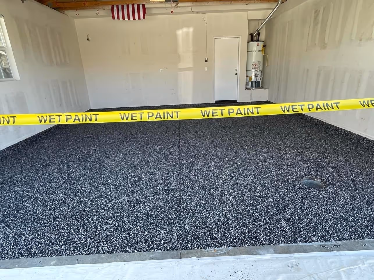 Freshly coated dark epoxy flake garage floor taped off with wet paint tape while it cures
