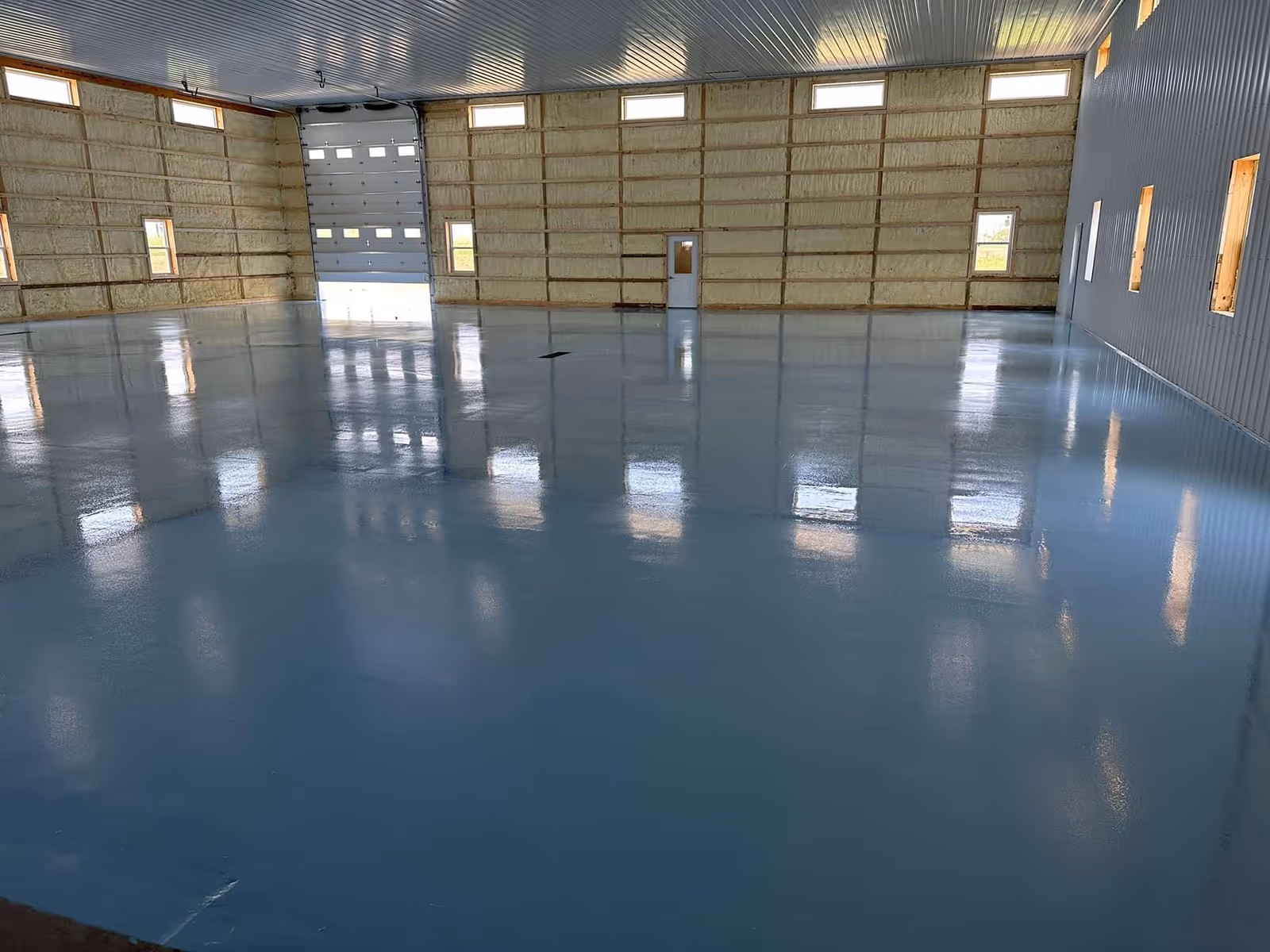Blue resin floor across a large distribution shed with the shutter doors at the far end