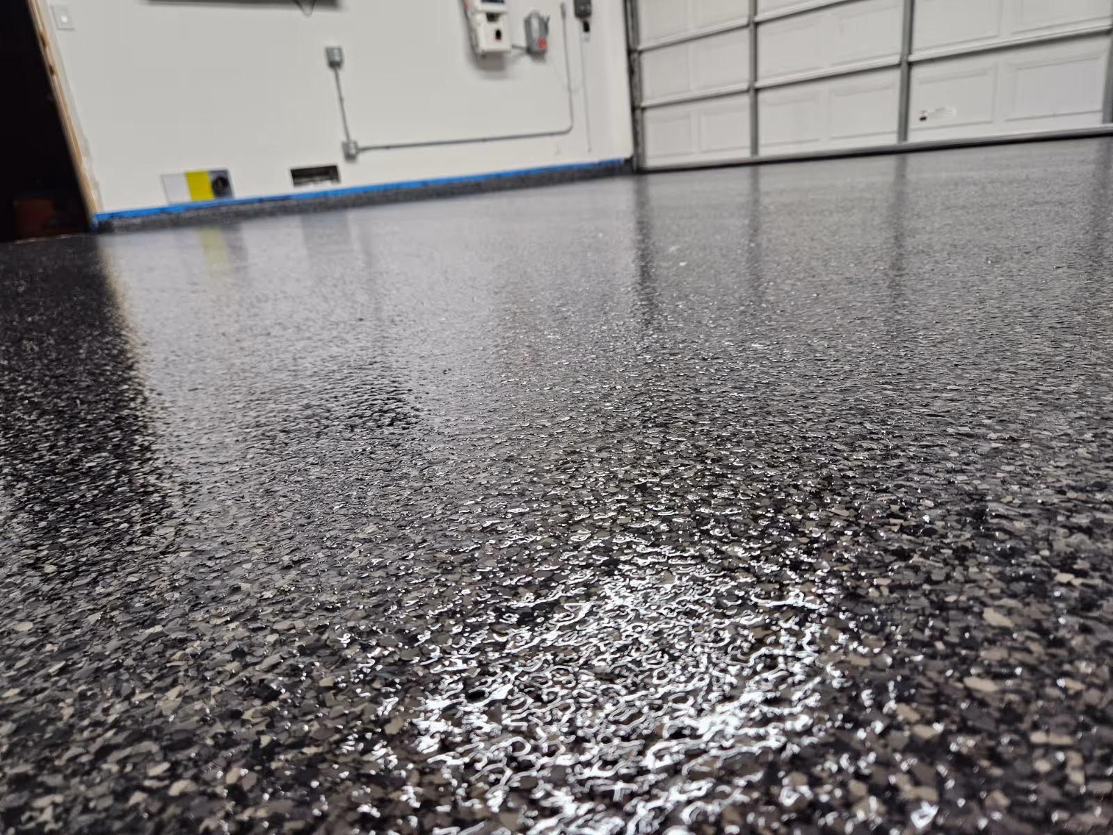 Close-up of a black and gray flake garage floor near the door line