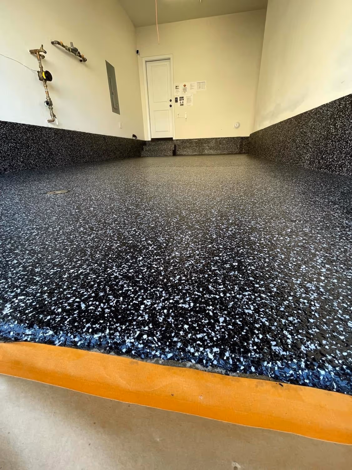 Dark blue and black flake garage floor with a coved base and a step up to the house door