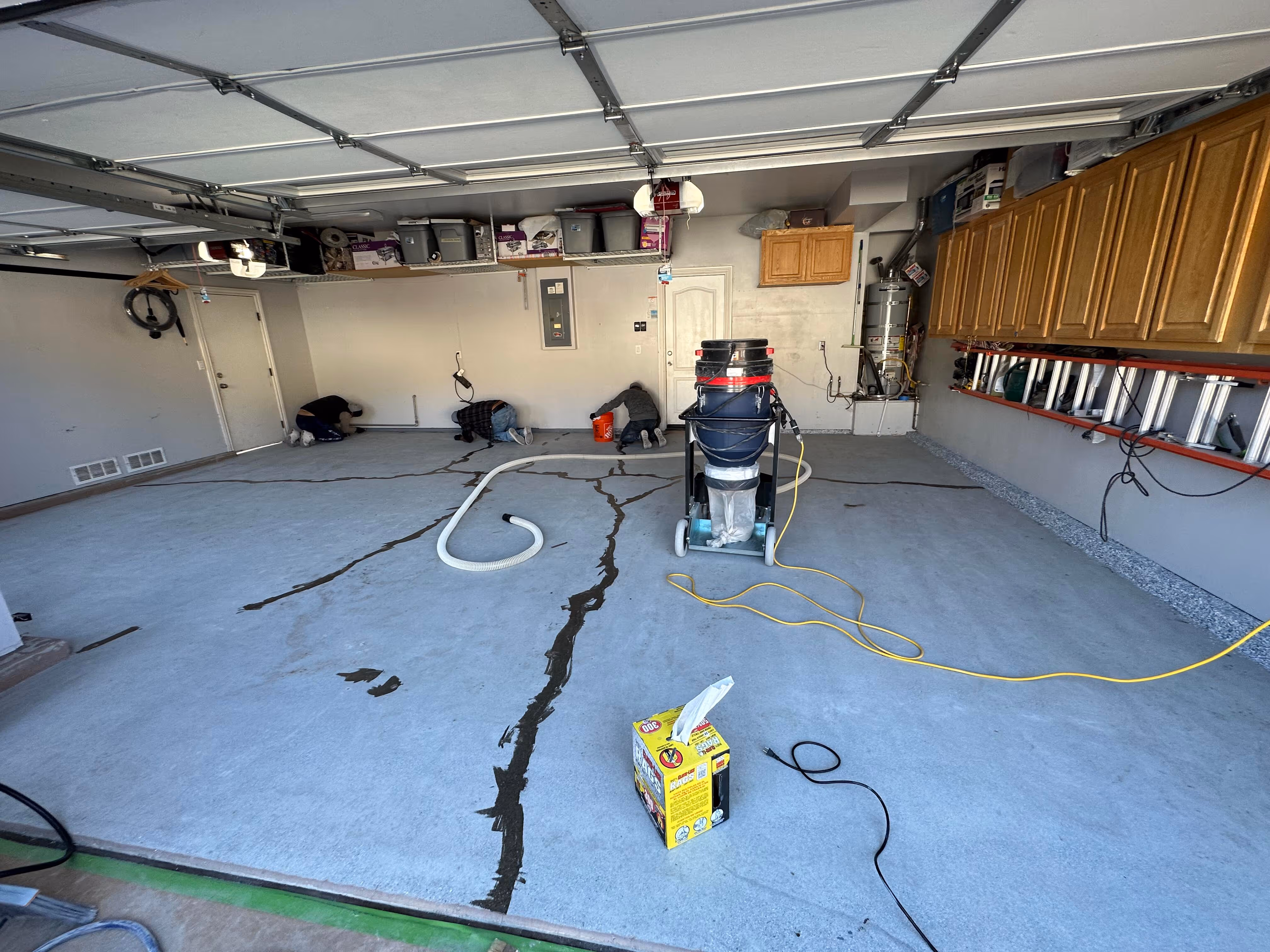Garage floor installation underway with grinding equipment and hoses in place