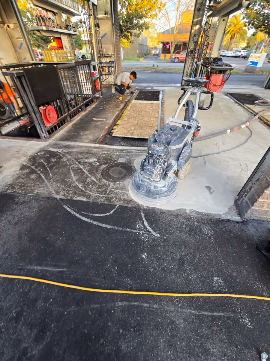 Concrete floor being refined by a planetary grinder inside a commercial service bay