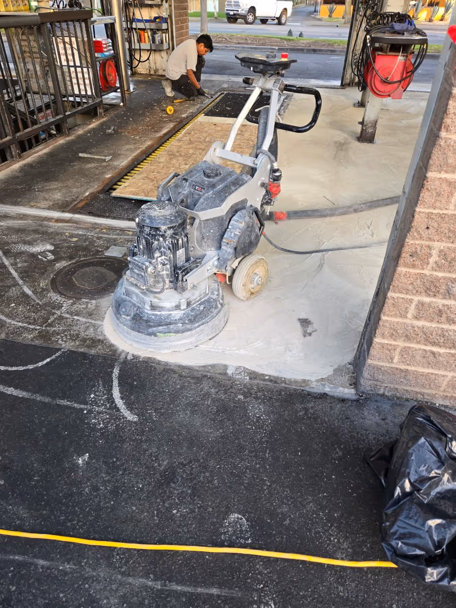Planetary grinder refining a concrete floor at a commercial entrance with the operator working behind it