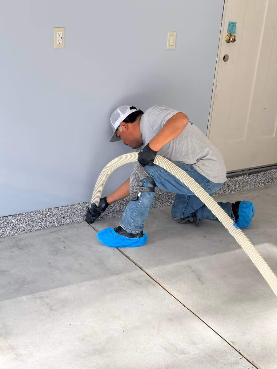 Installer grinding a garage floor edge with dust extraction