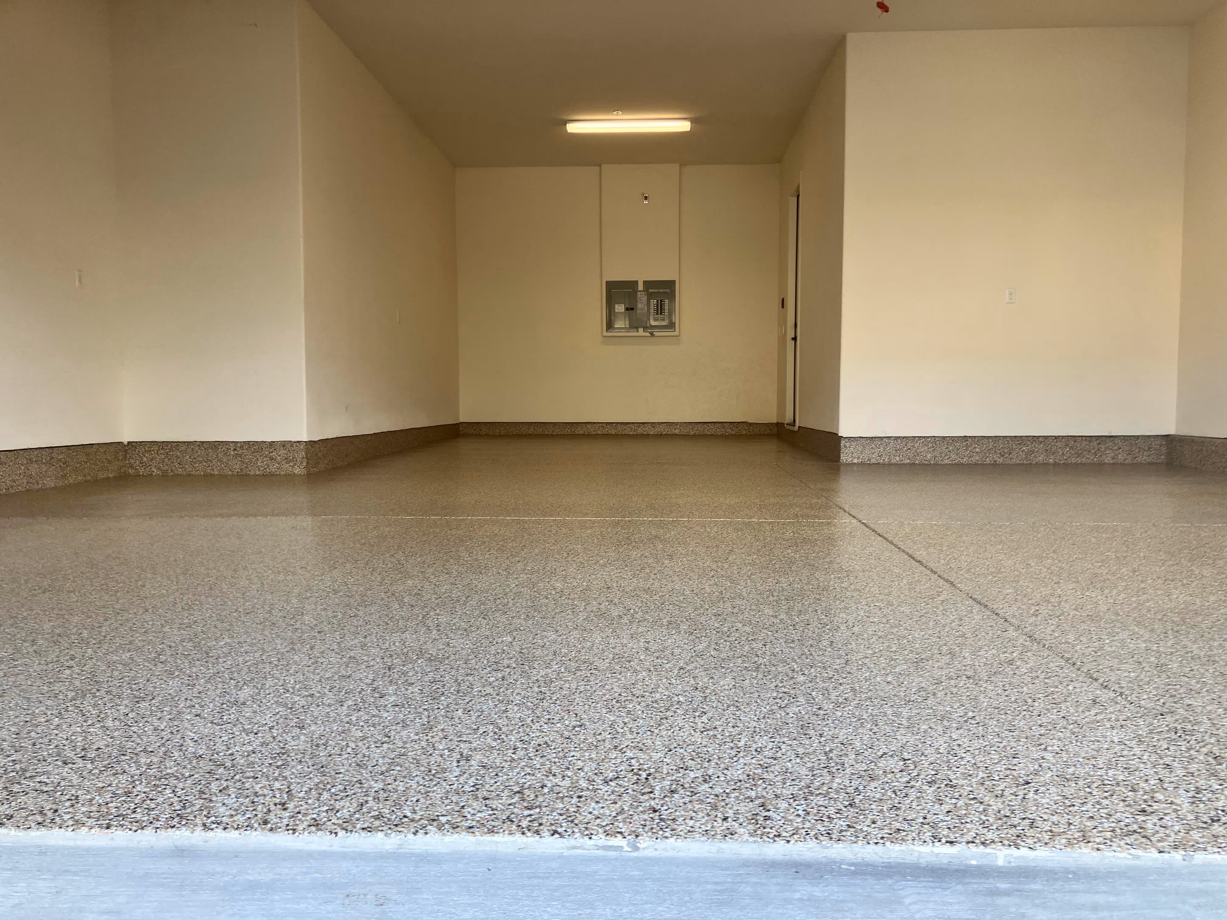 Finished tan epoxy flake floor in an empty two-car garage