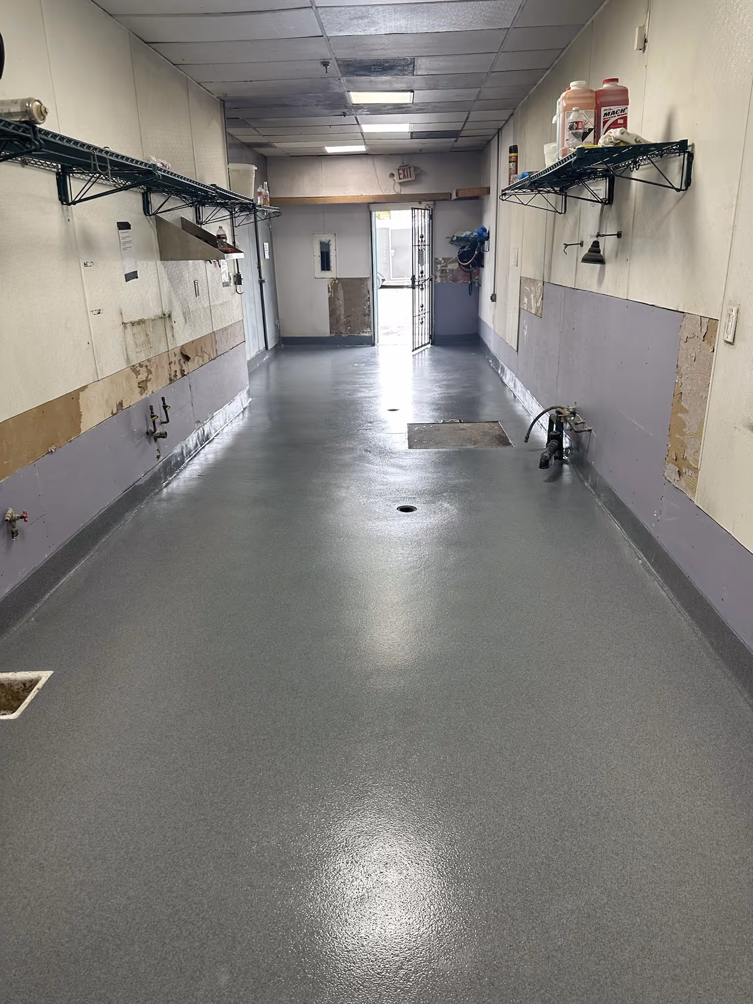 Seamless gray resin floor with a coved base running past stainless steel shelving