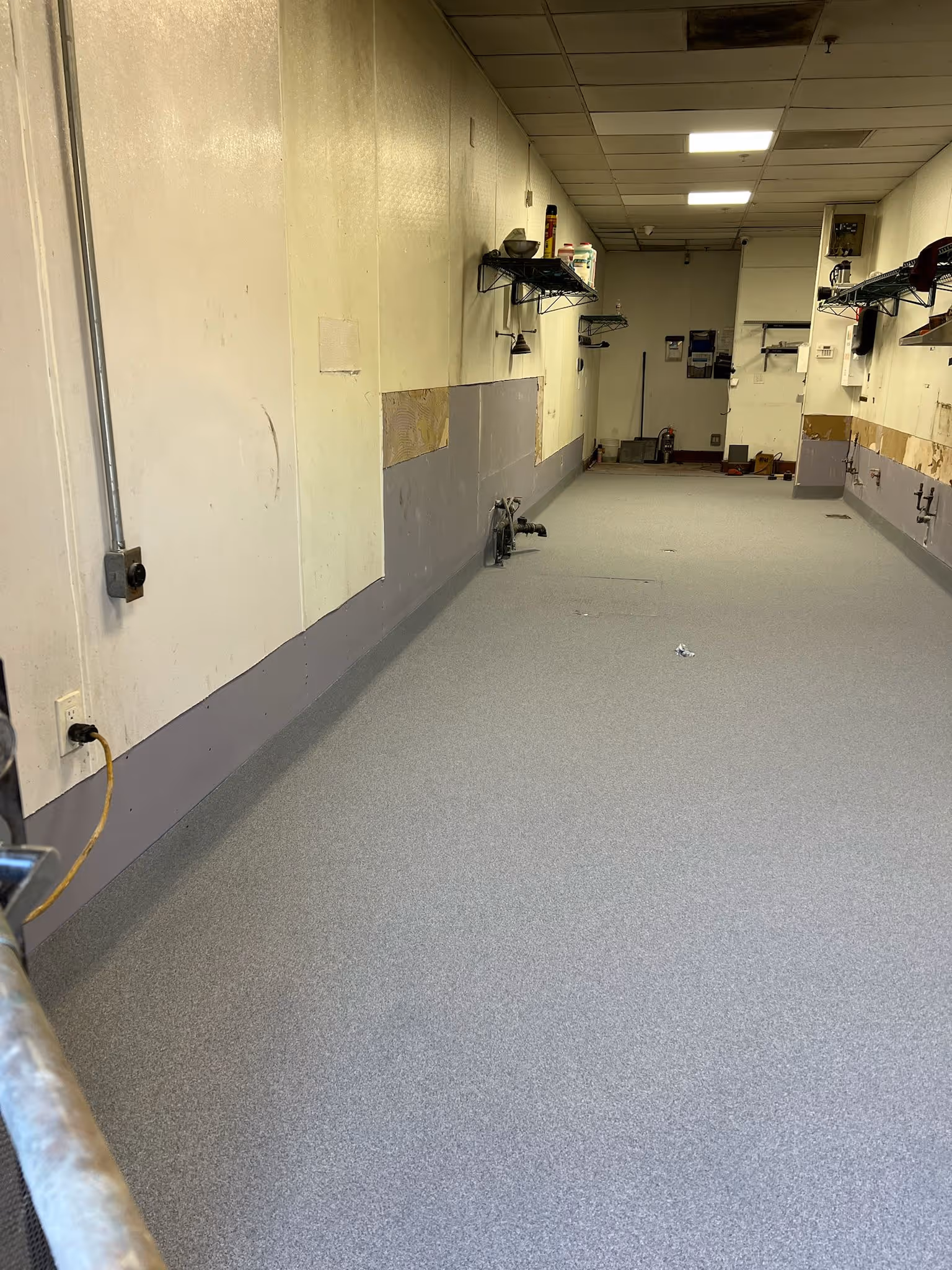 Seamless light gray resin floor with a coved base in a commercial food preparation corridor