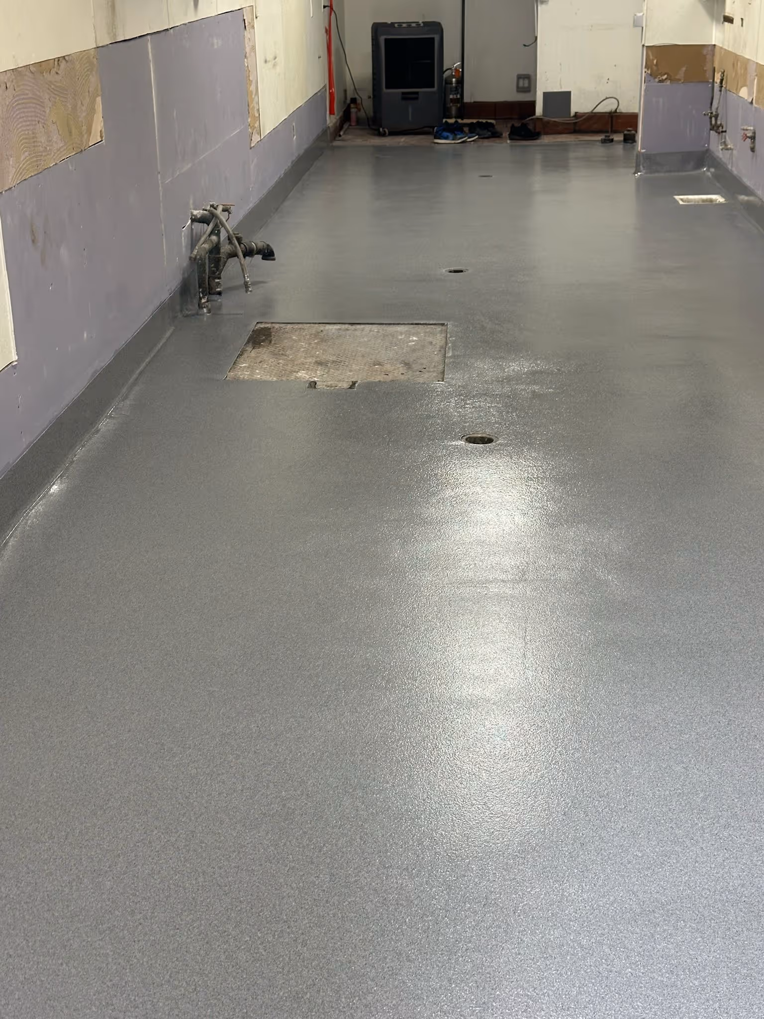 Seamless gray resin floor after wash down with water draining across the surface