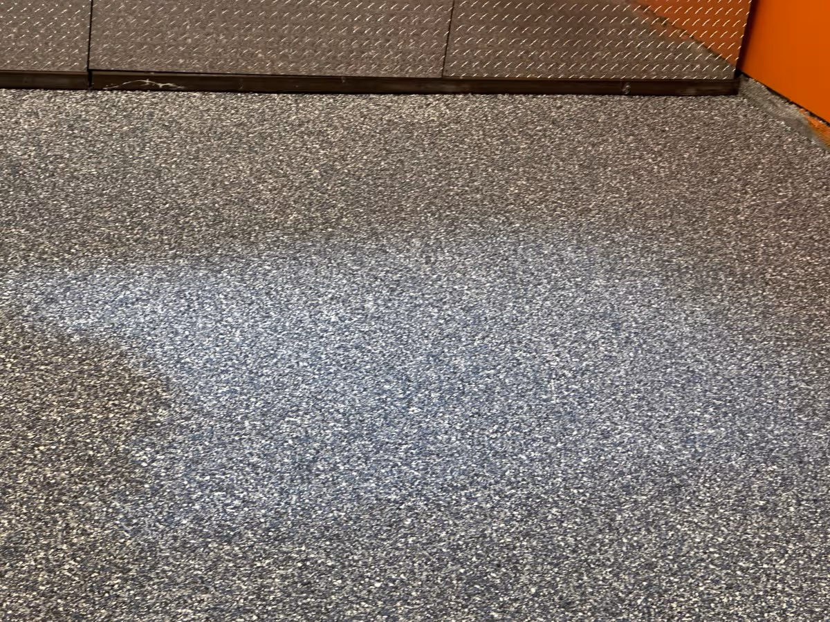 Blue and gray flake floor finished on a clean edge against a checker plate threshold