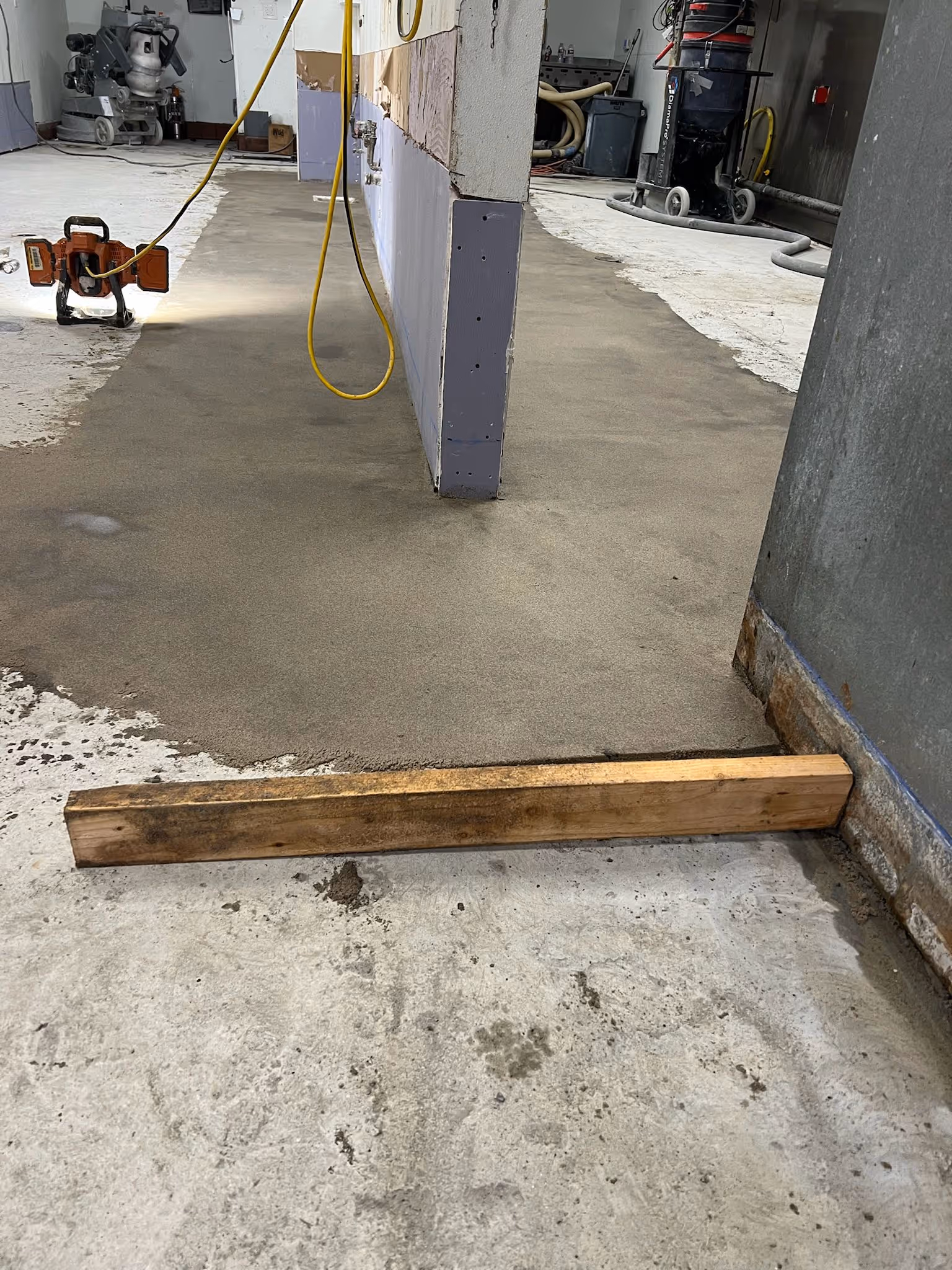 Concrete slab being leveled with a screed board before the floor system is applied