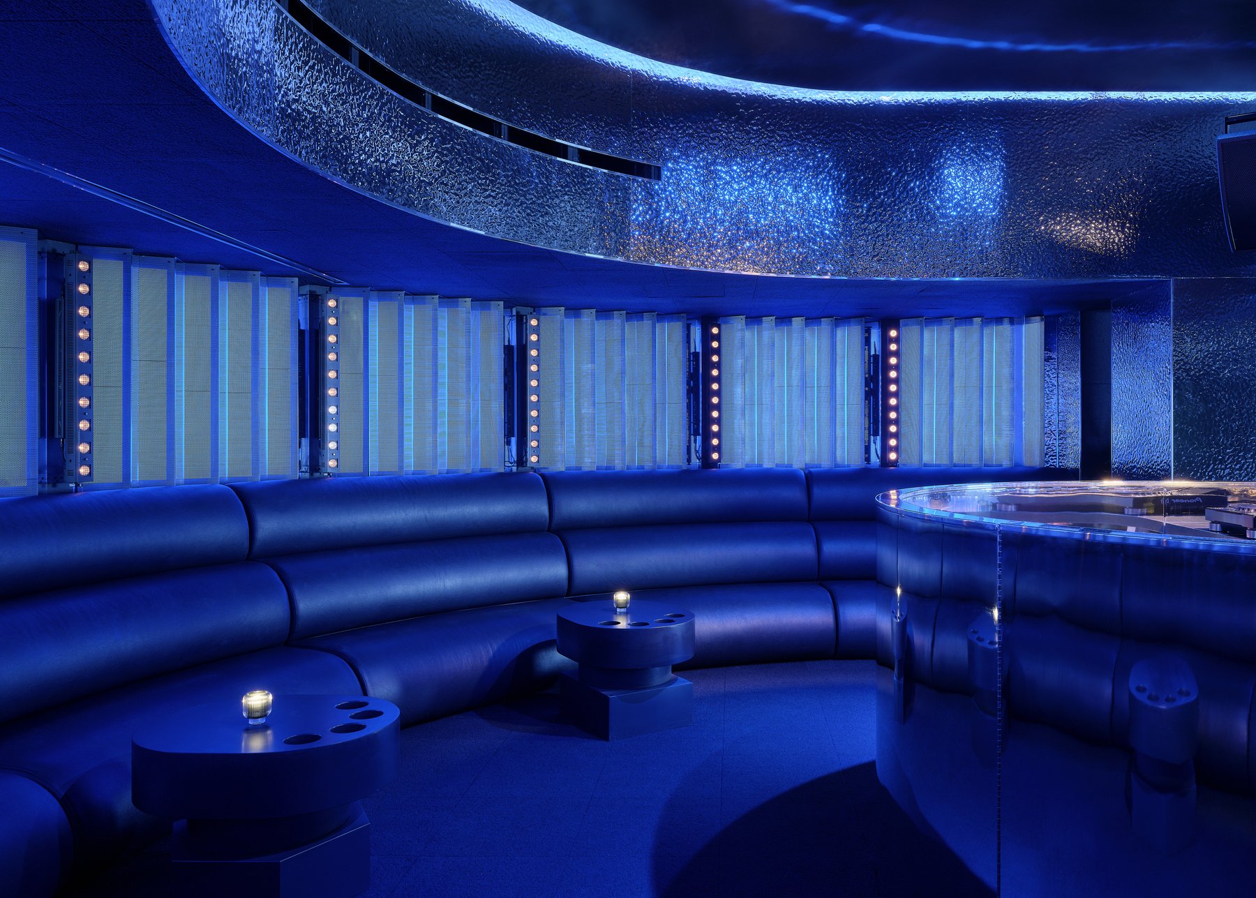 Blue-lit curved seating and tables inside Unveiled