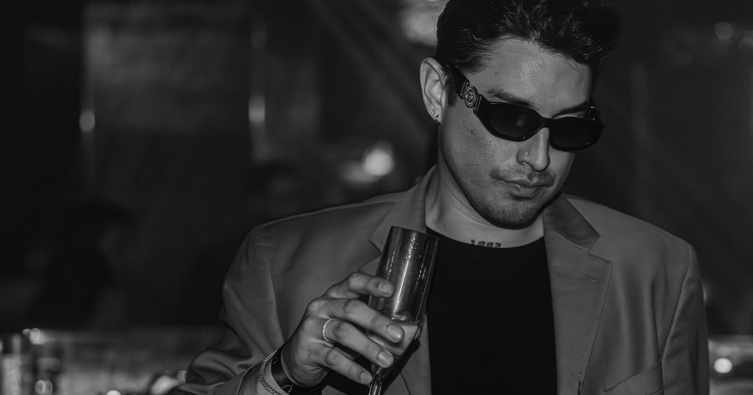 Guest in tailored evening attire holding a champagne flute inside Unveiled.