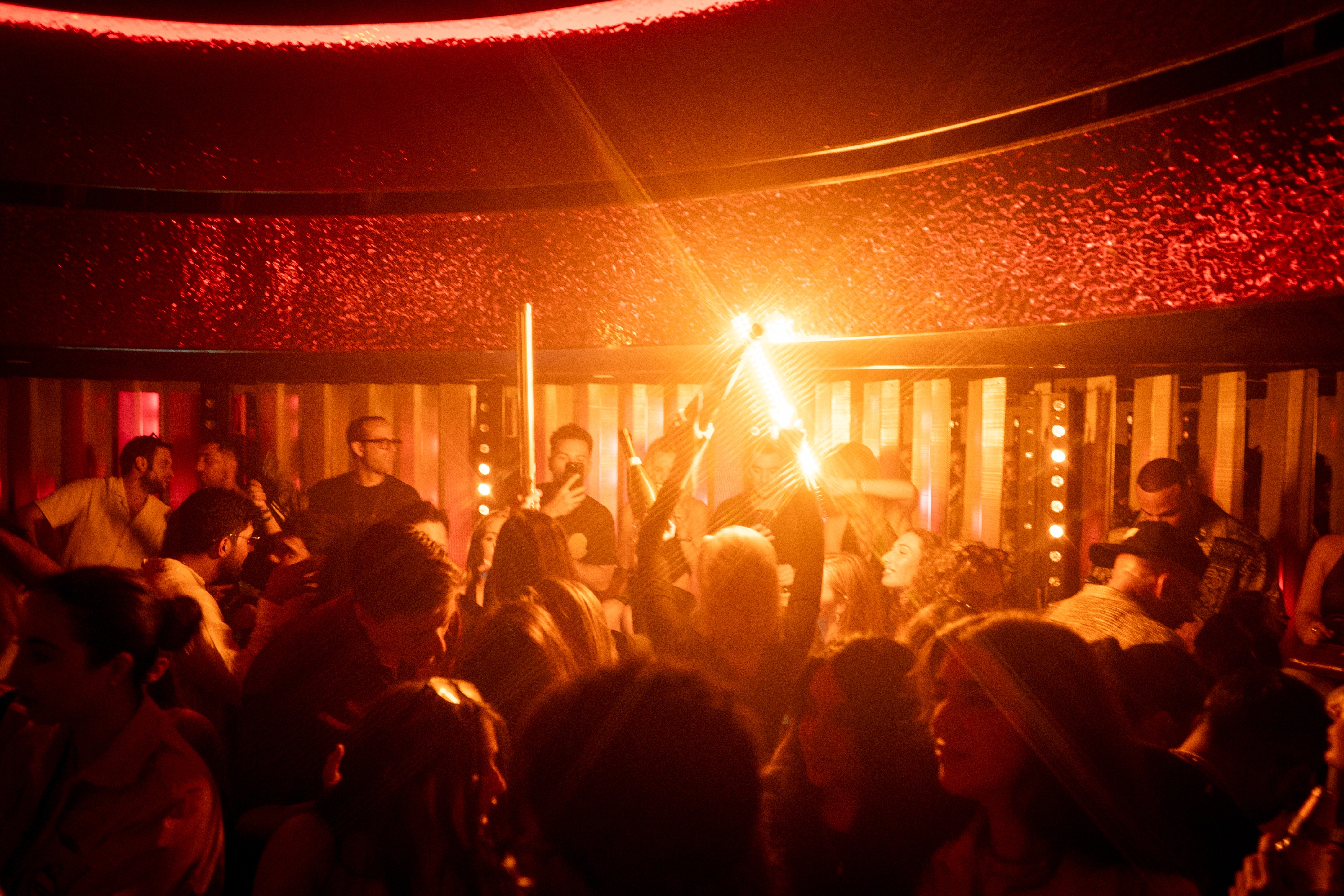 Guests gathered beneath warm amber lighting in an Unveiled interior.