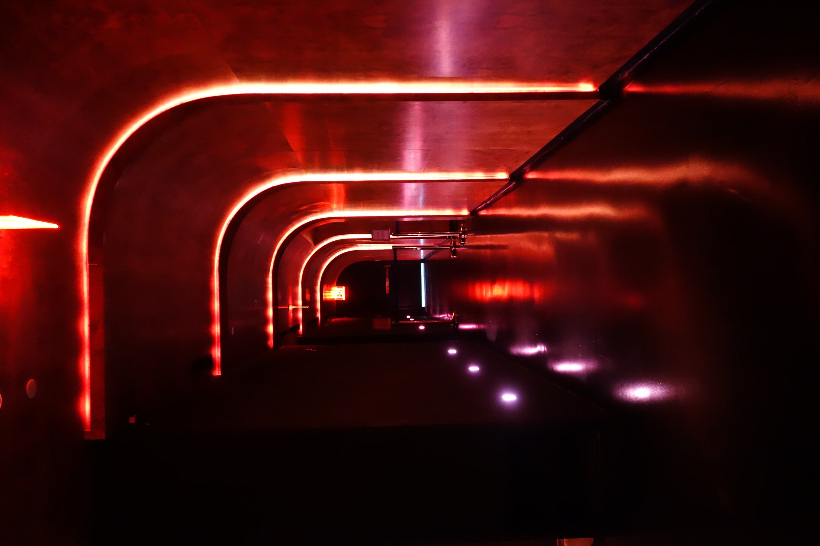 Red arched interior with linear lighting at Unveiled in Williamsburg, Brooklyn.
