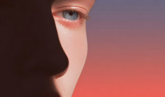 Close-up of a person's face with blue eye against a gradient orange to purple background.