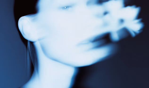 Blurred close-up of a person's face with smoke or mist obscuring the features.