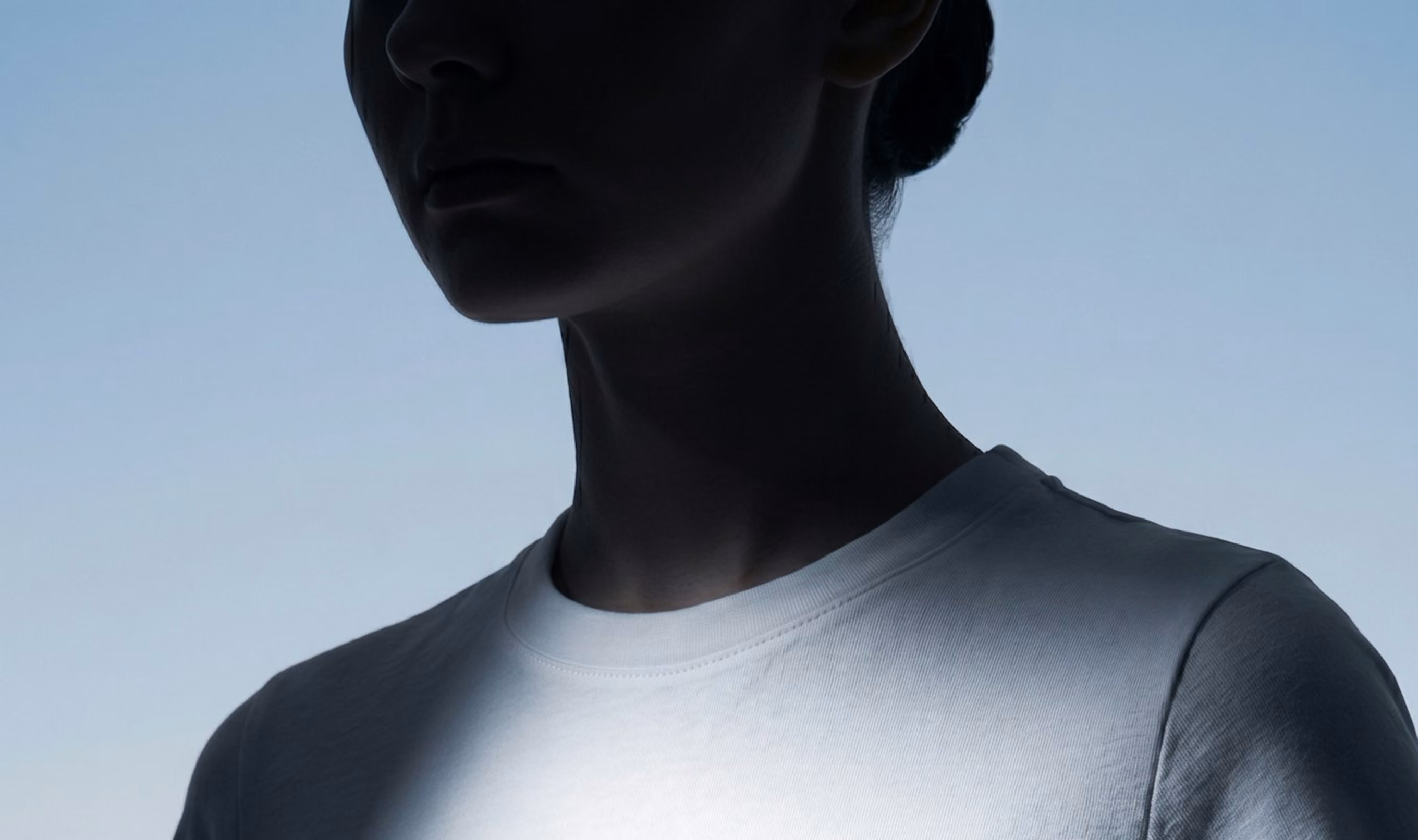 Silhouette of a person wearing a white shirt against a light blue background.
