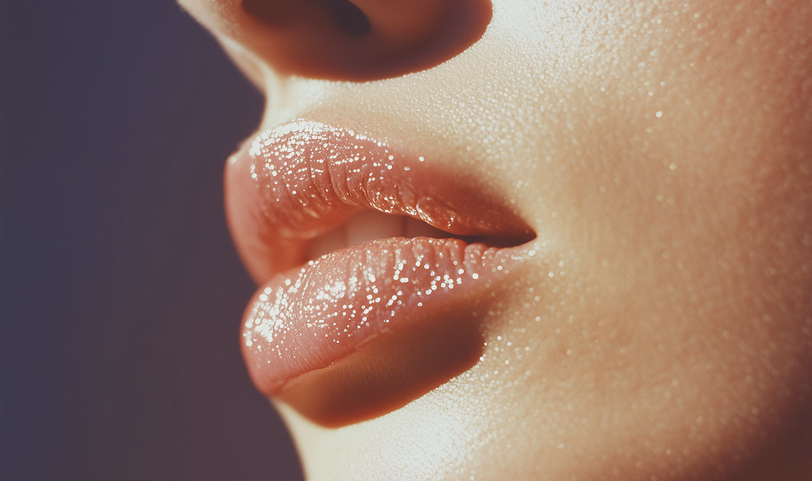Close-up of glossy, moisturized lips and smooth skin with shiny highlights.