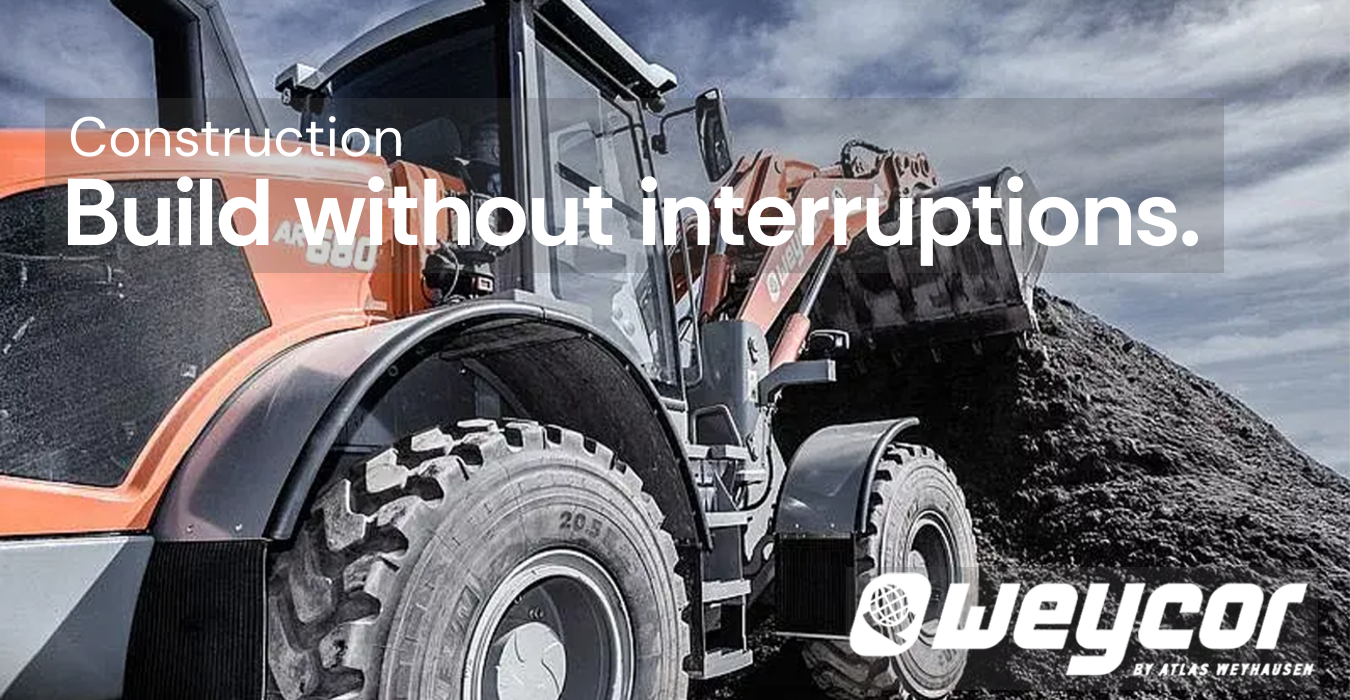Heavy construction vehicle with a front loader lifting a large pile of dirt under a cloudy sky.
