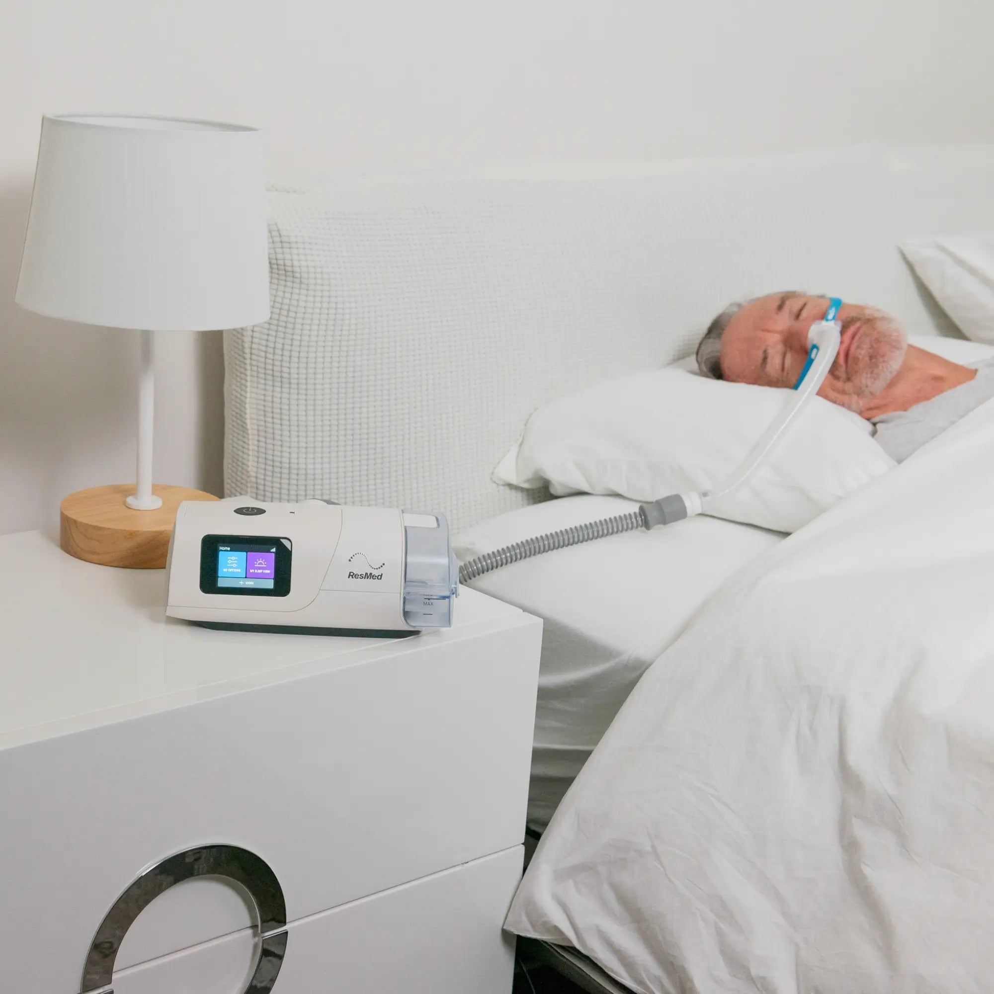 Man sleeping with mask connected to ResMed AirCurve 11 VAuto on bedside table