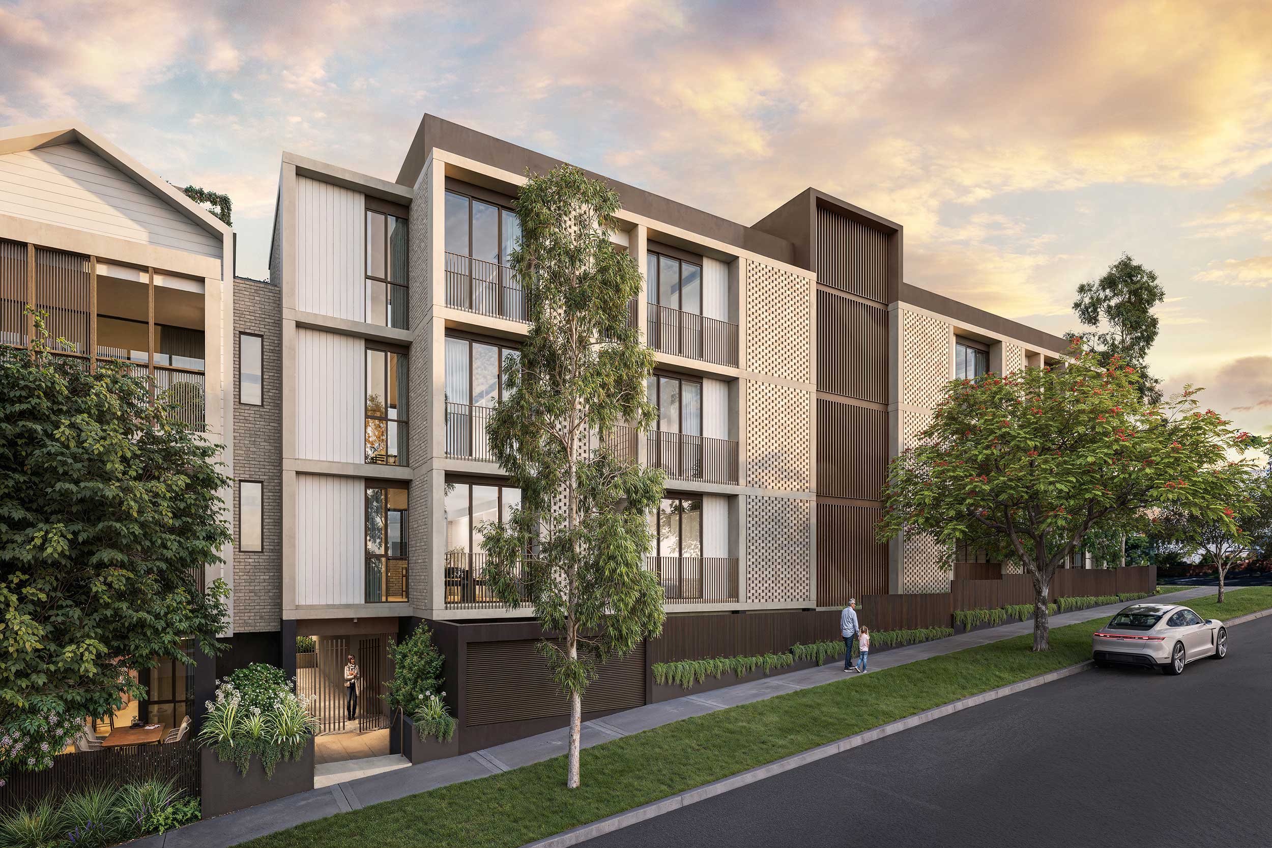 Modern four-story apartment building with balconies, trees, a sidewalk, and a parked silver car.
