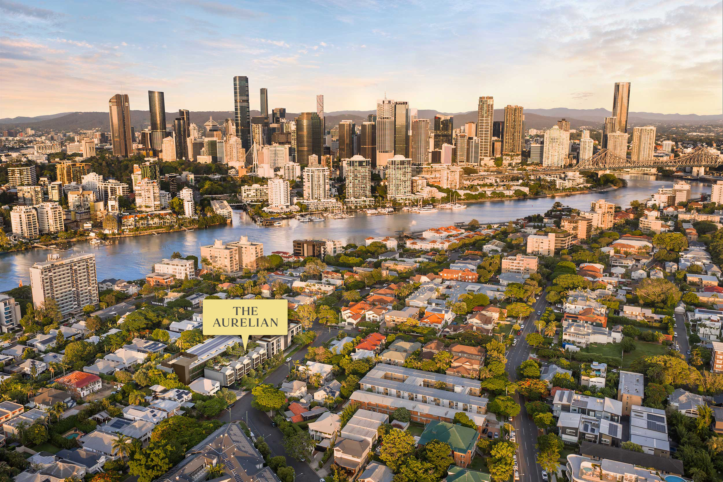 Aerial view of a city skyline at sunset with a river and residential areas in the foreground.