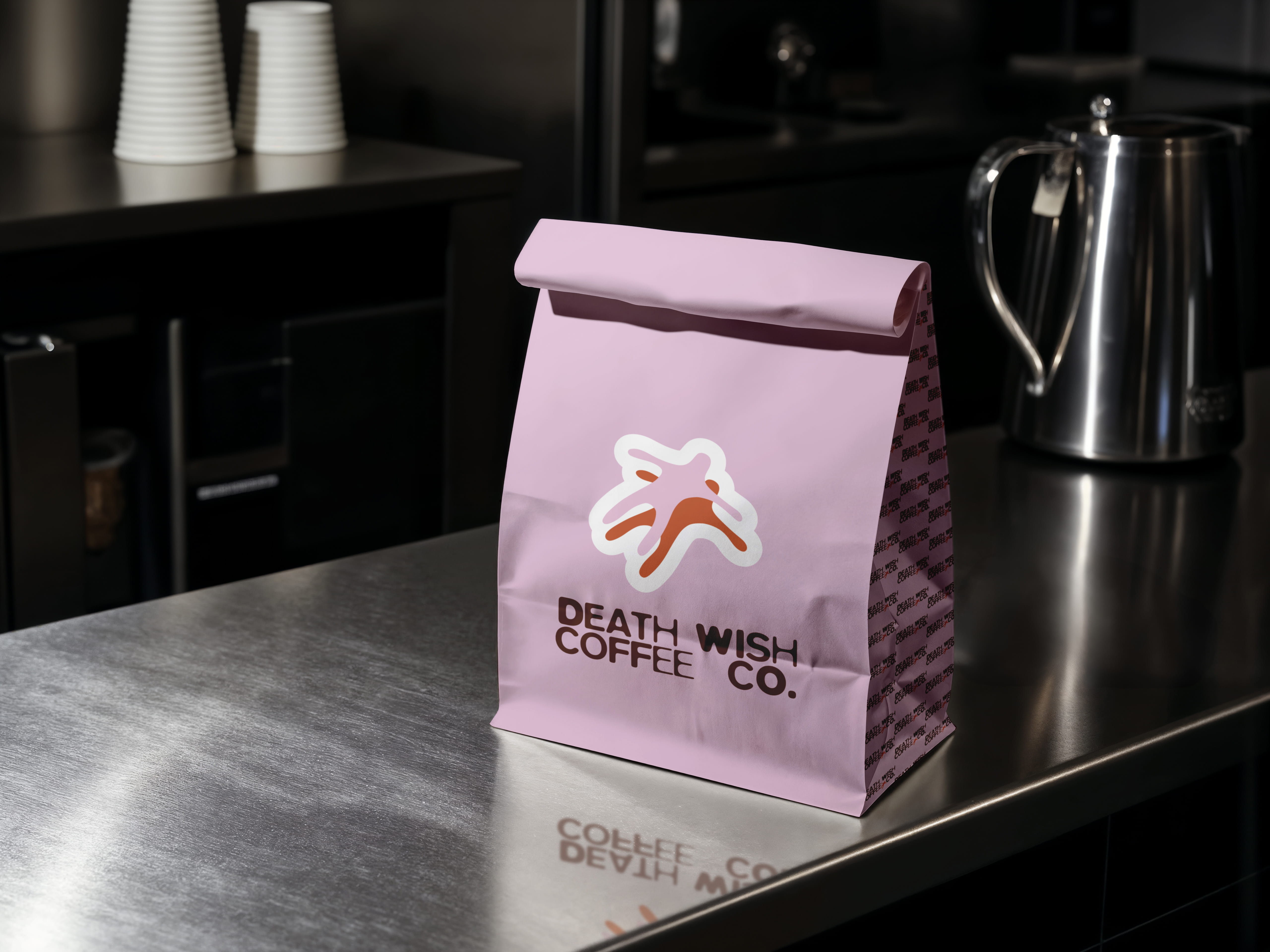 mockup found on magnific -Pink paper bag with Death Wish Coffee Co. logo and text on a stainless steel countertop.