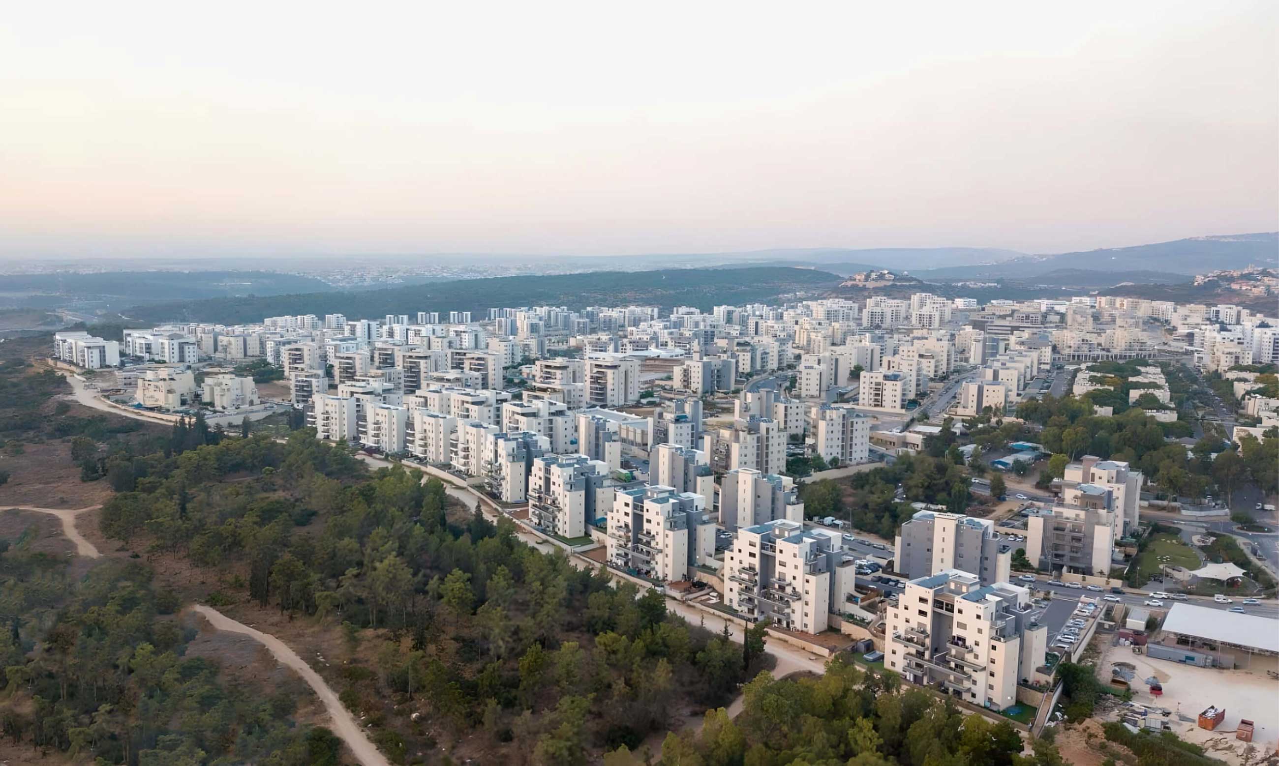 Aerial view of a large residential area with modern apartment buildings surrounded by greenery and hills.