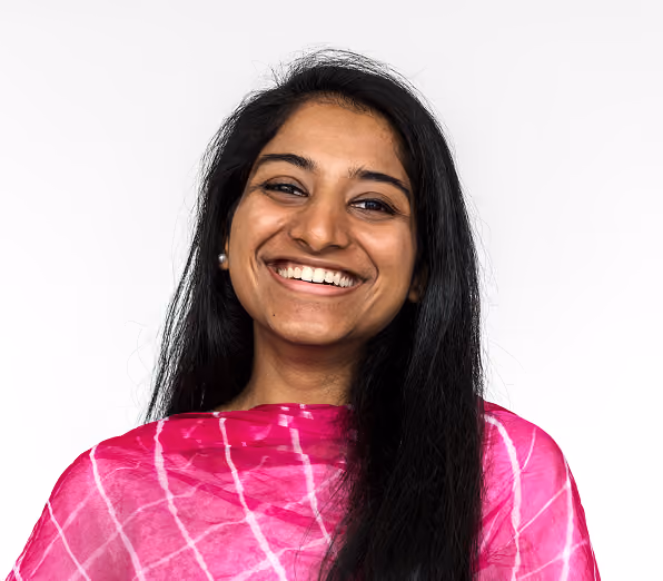 A woman with long black hair is smiling while wearing a pink and white patterned garment. The background is plain white, providing a neutral setting for the subject.