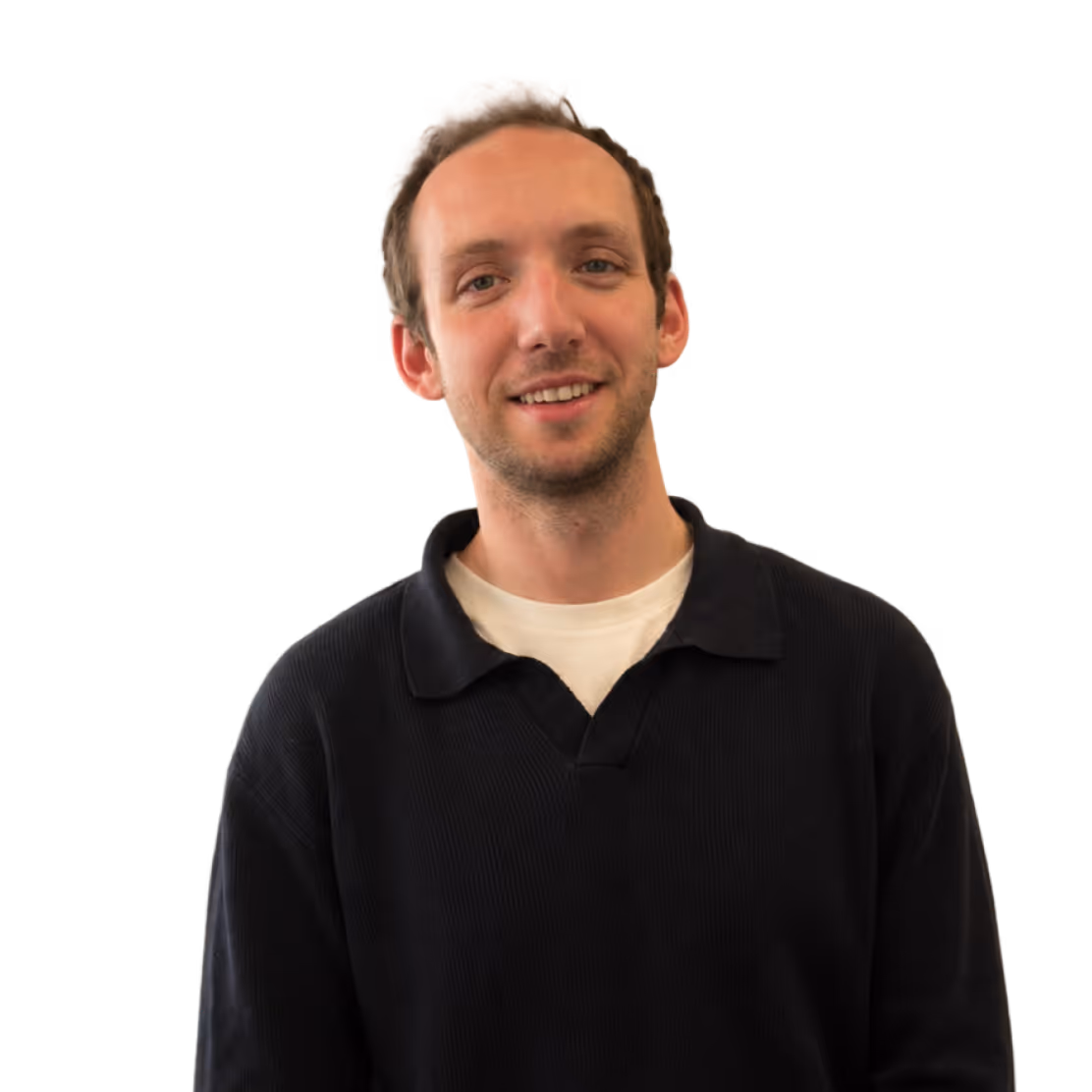 Smiling man with short hair wearing a black collared shirt over a white t-shirt.