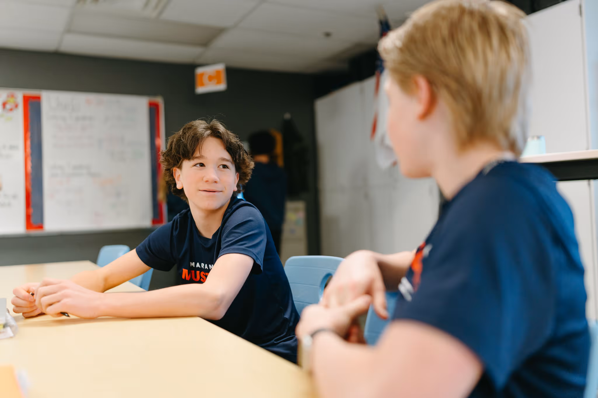 Middle school students conversing and learning together across a classroom table