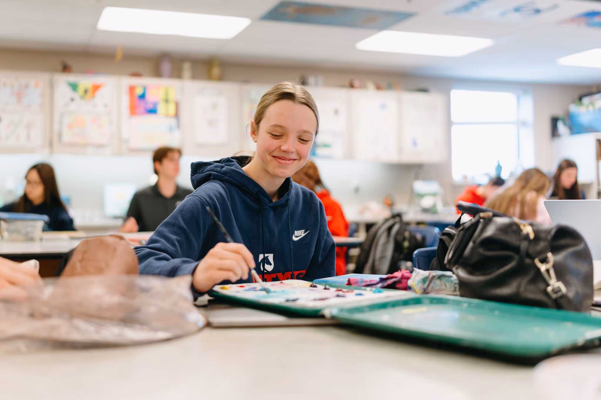 Student painting with watercolors at an art classroom table