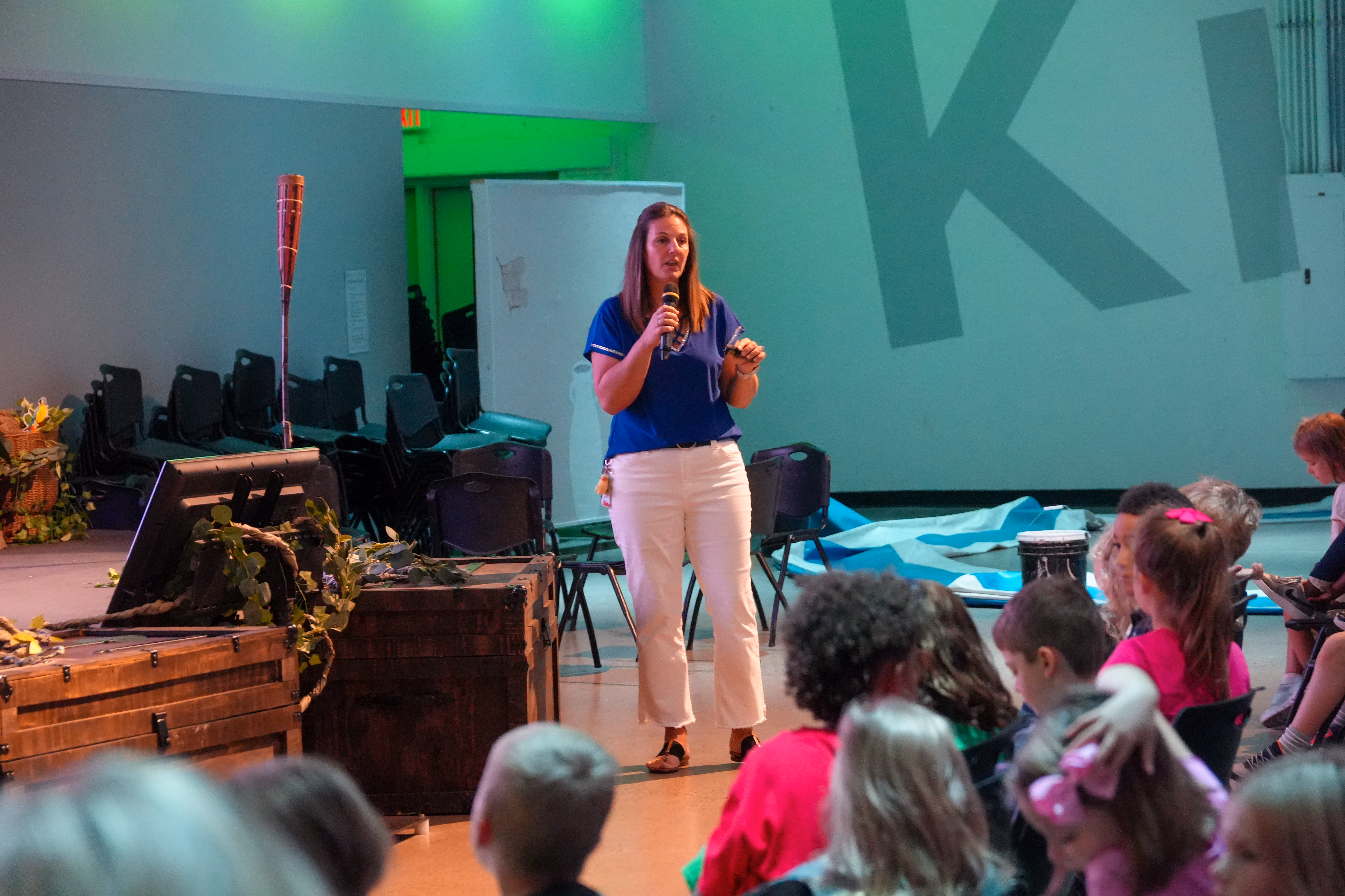 High school student speaking with a microphone on stage during a presentation.