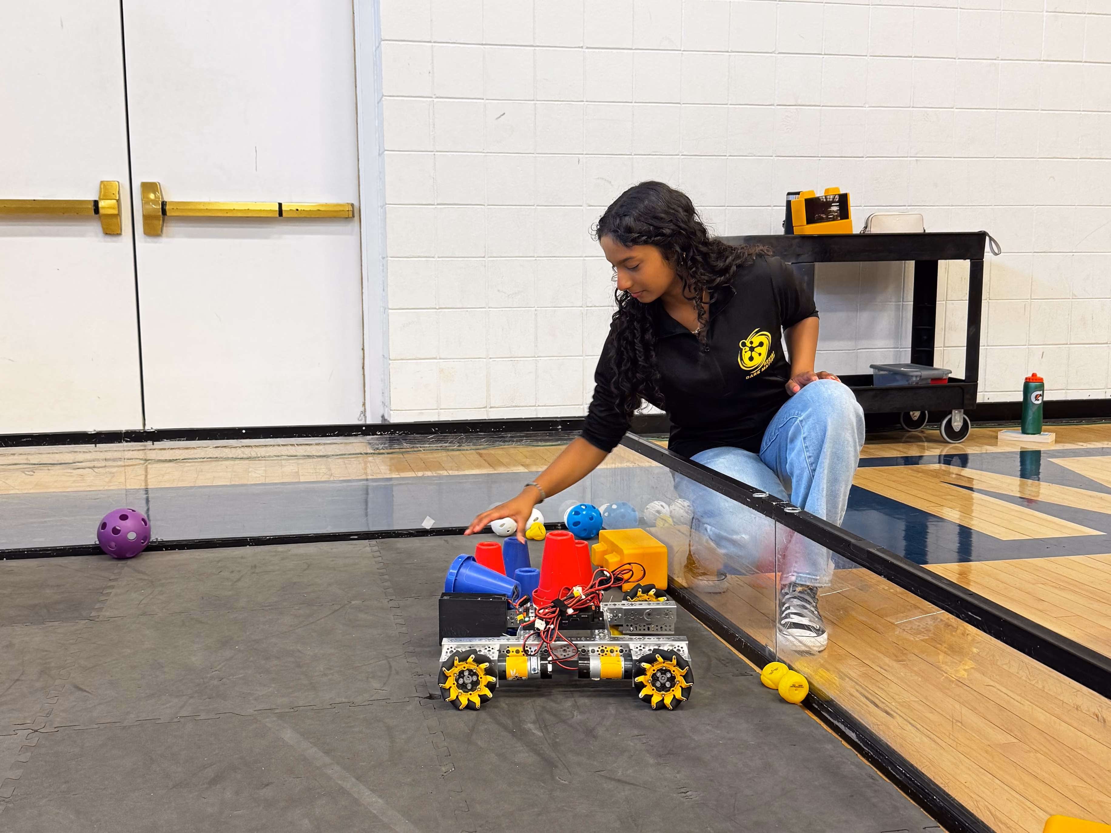Middle school student positioning a LEGO Mindstorms EV3 robot on an indoor obstacle course