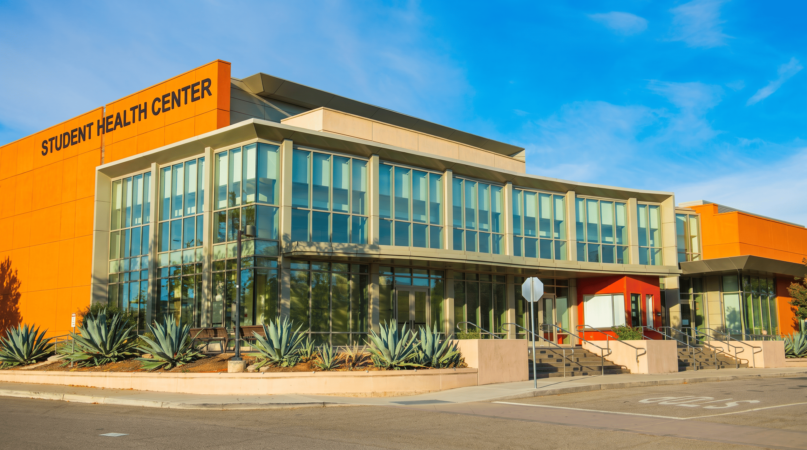 Modern Student Health Center facility with bright orange exterior and glass frontage, representing contemporary university campus healthcare infrastructure. 
