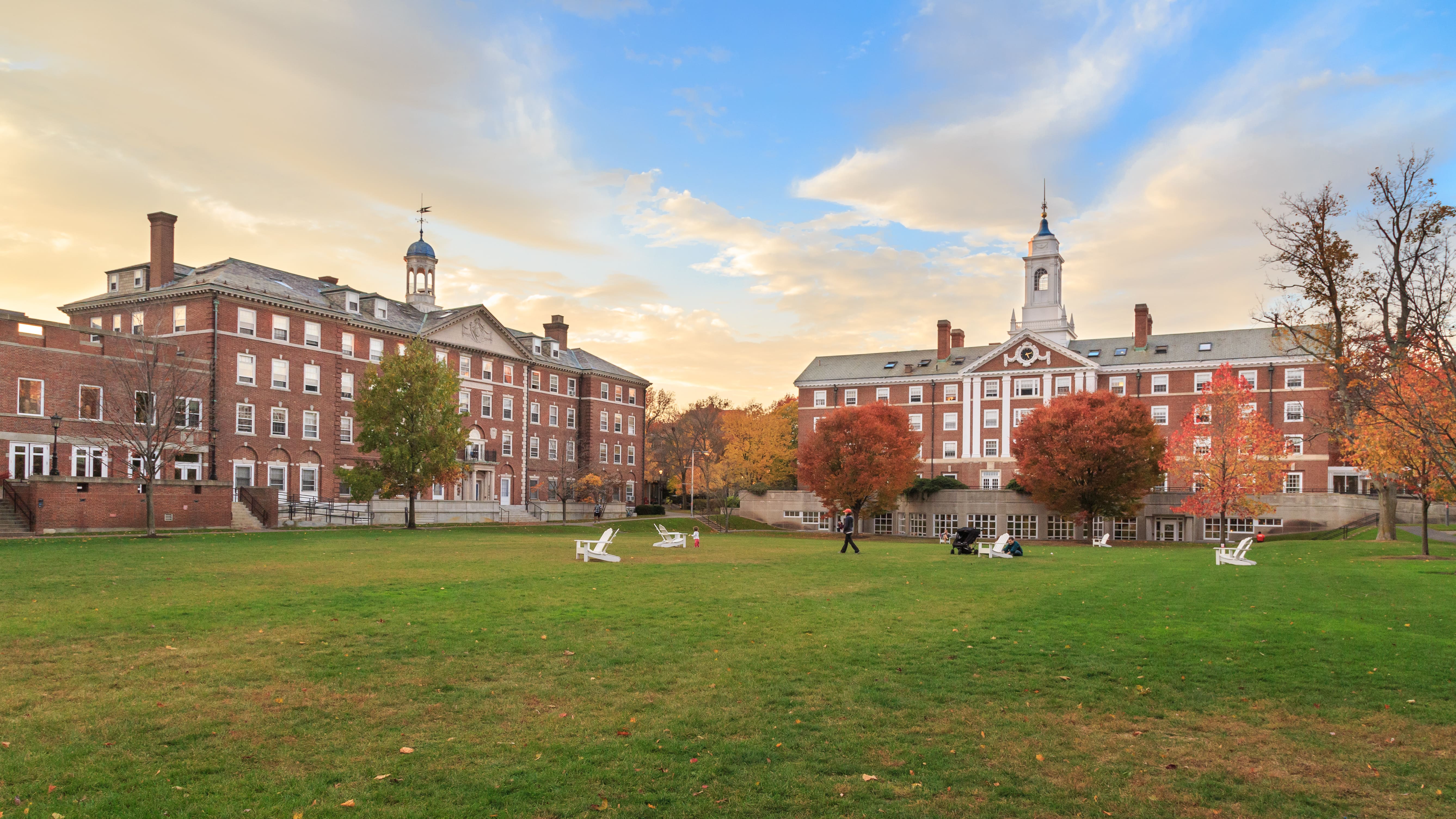 Traditional college campus quad with brick academic buildings and students, representing higher education environment for student healthcare access.