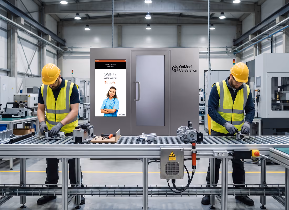 Warehouse workers in hard hats working along an assembly line beside an OnMed CareStation™