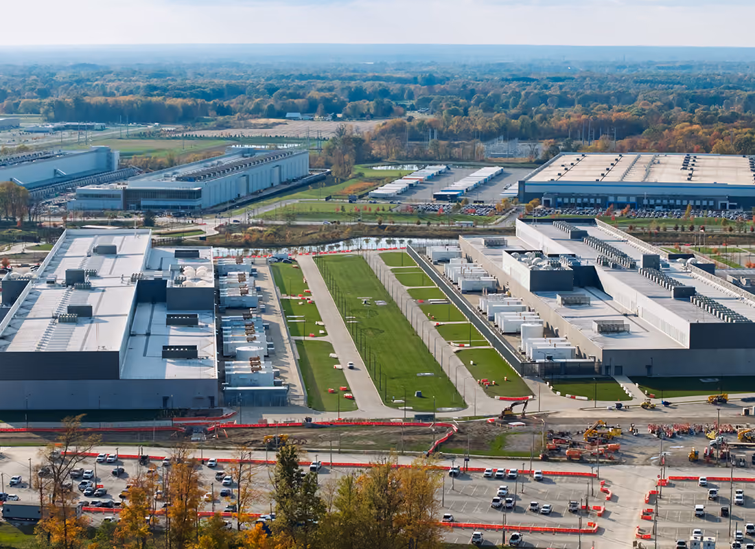 Aerial view of a large data center campus with rows of server buildings surrounded by trees and parking lots