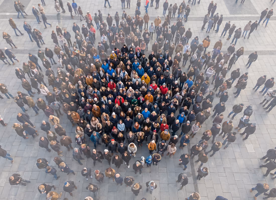 Aerial view of a large crowd gathered outdoors, forming a shape with people in colored jackets at the center