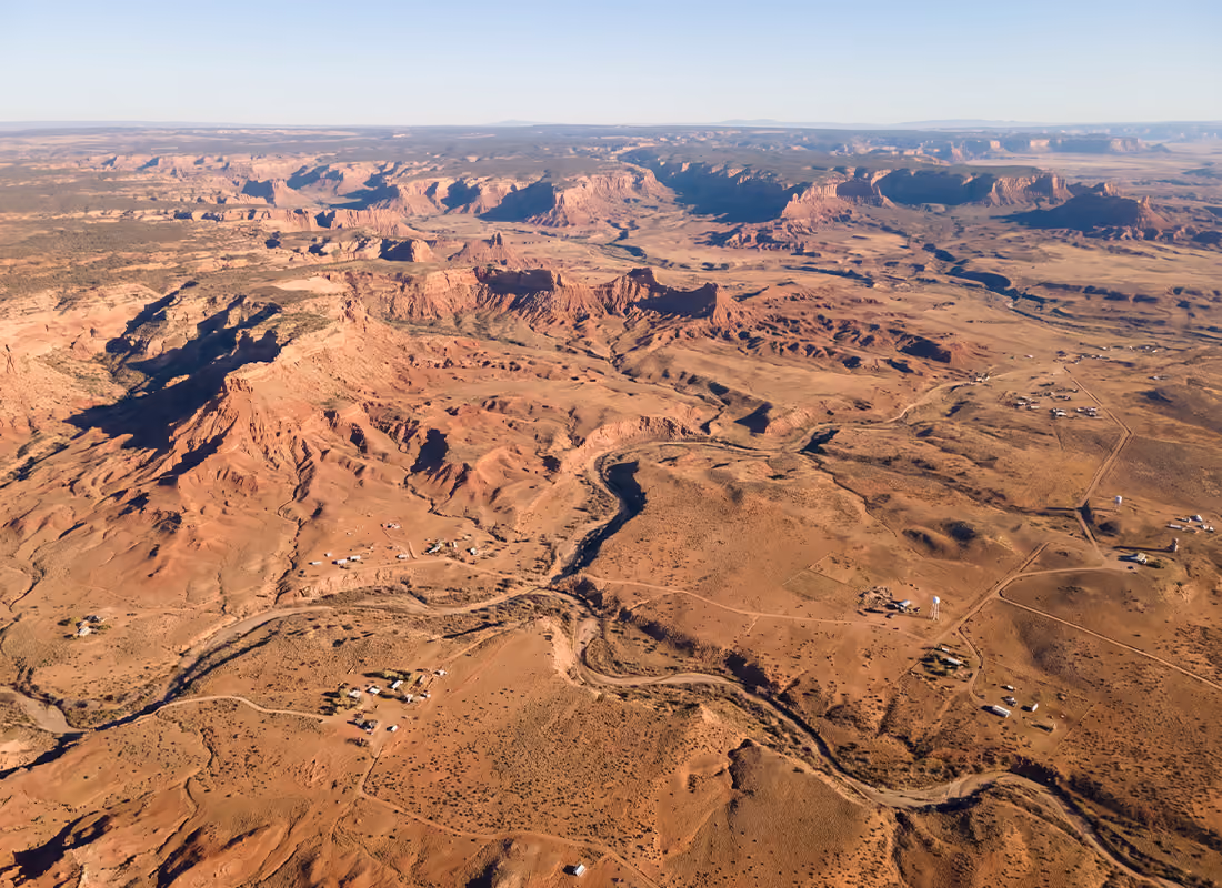 Aerial view of a desert canyon landscape with a winding river and scattered rural homes